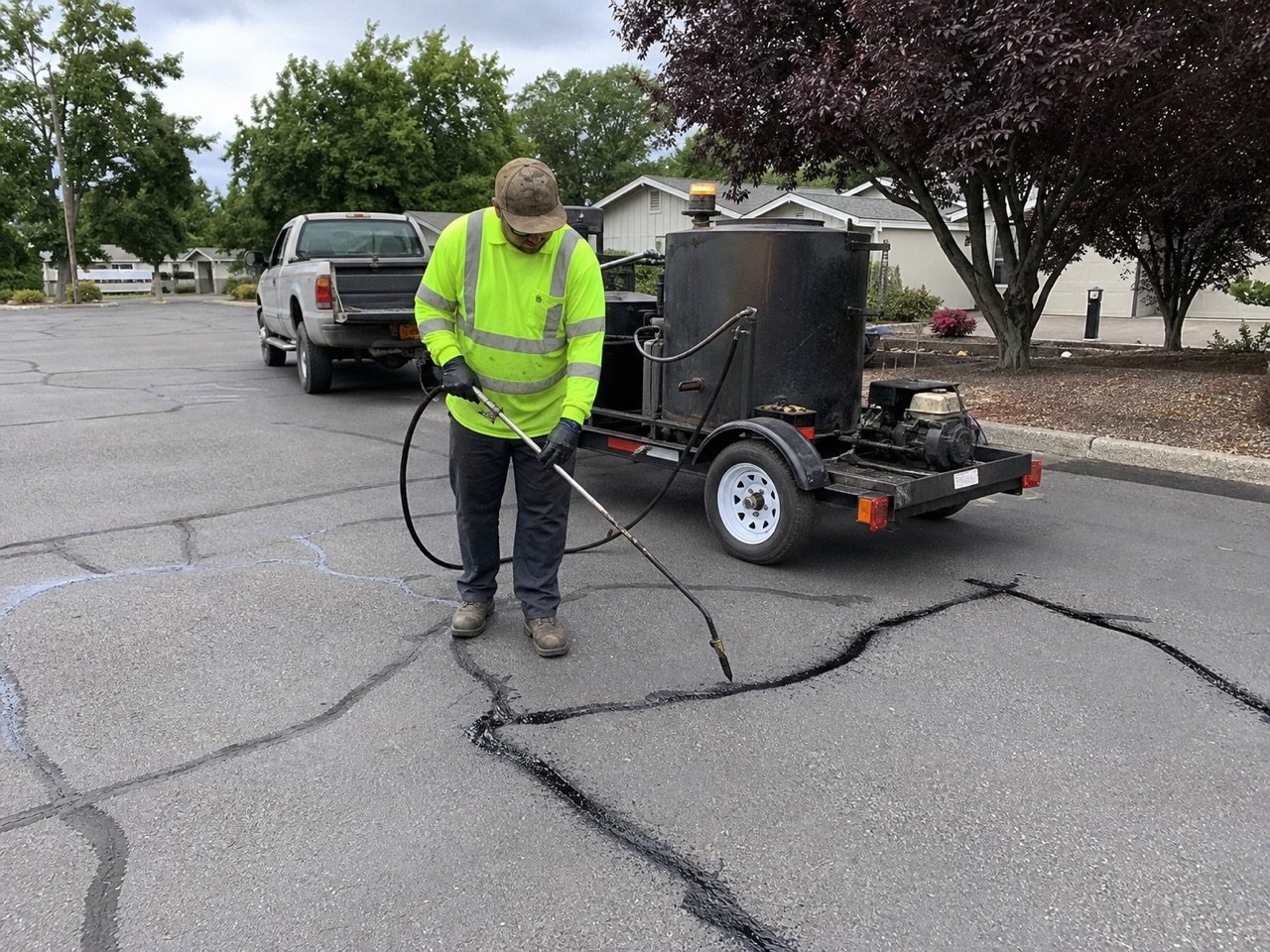 Worker applying hot rubberized sealant to an asphalt crack
