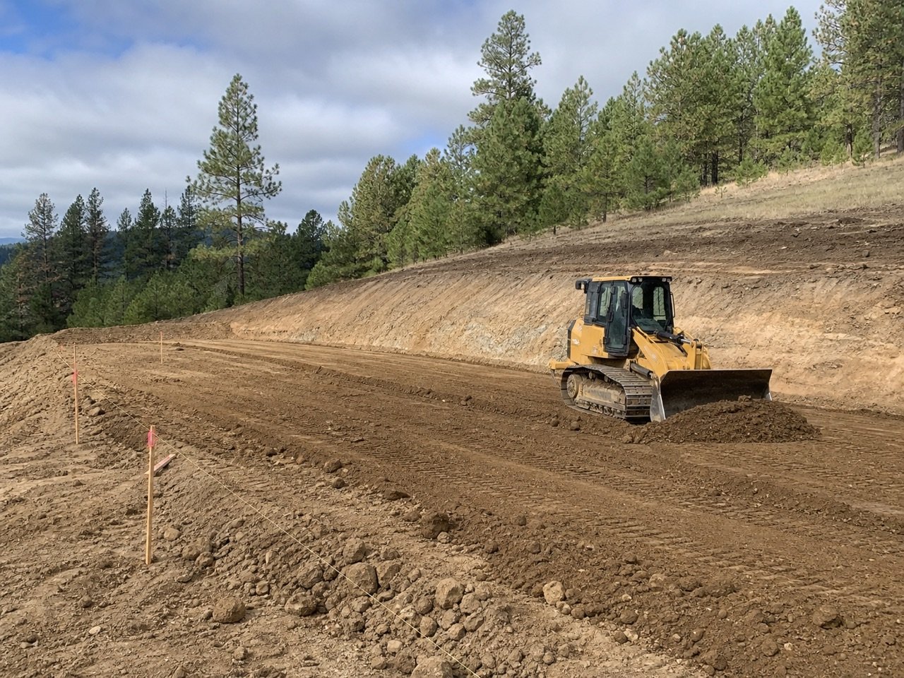 Track loader leveling a staked construction pad