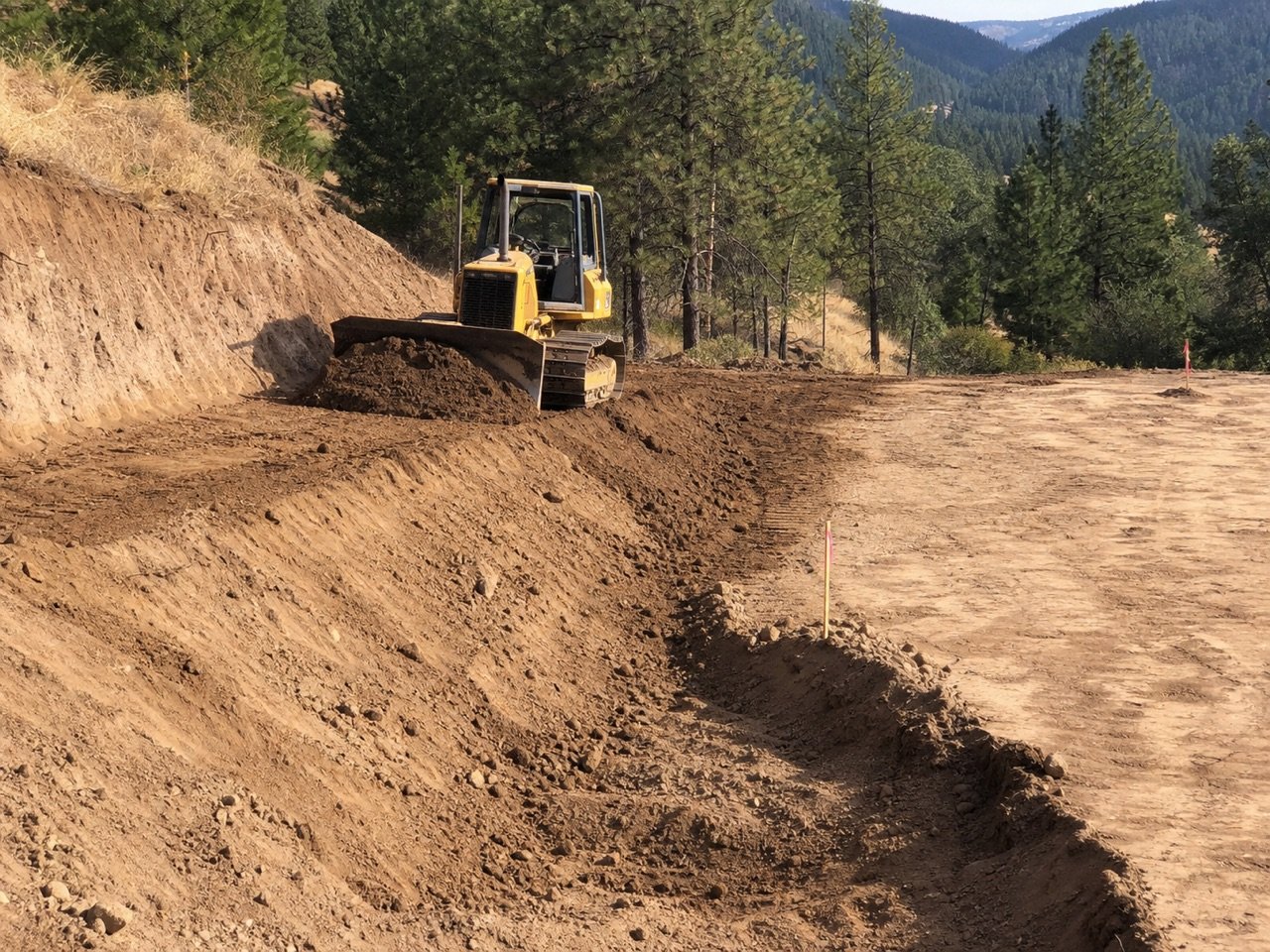 Bulldozer cutting and shaping a raw-earth slope