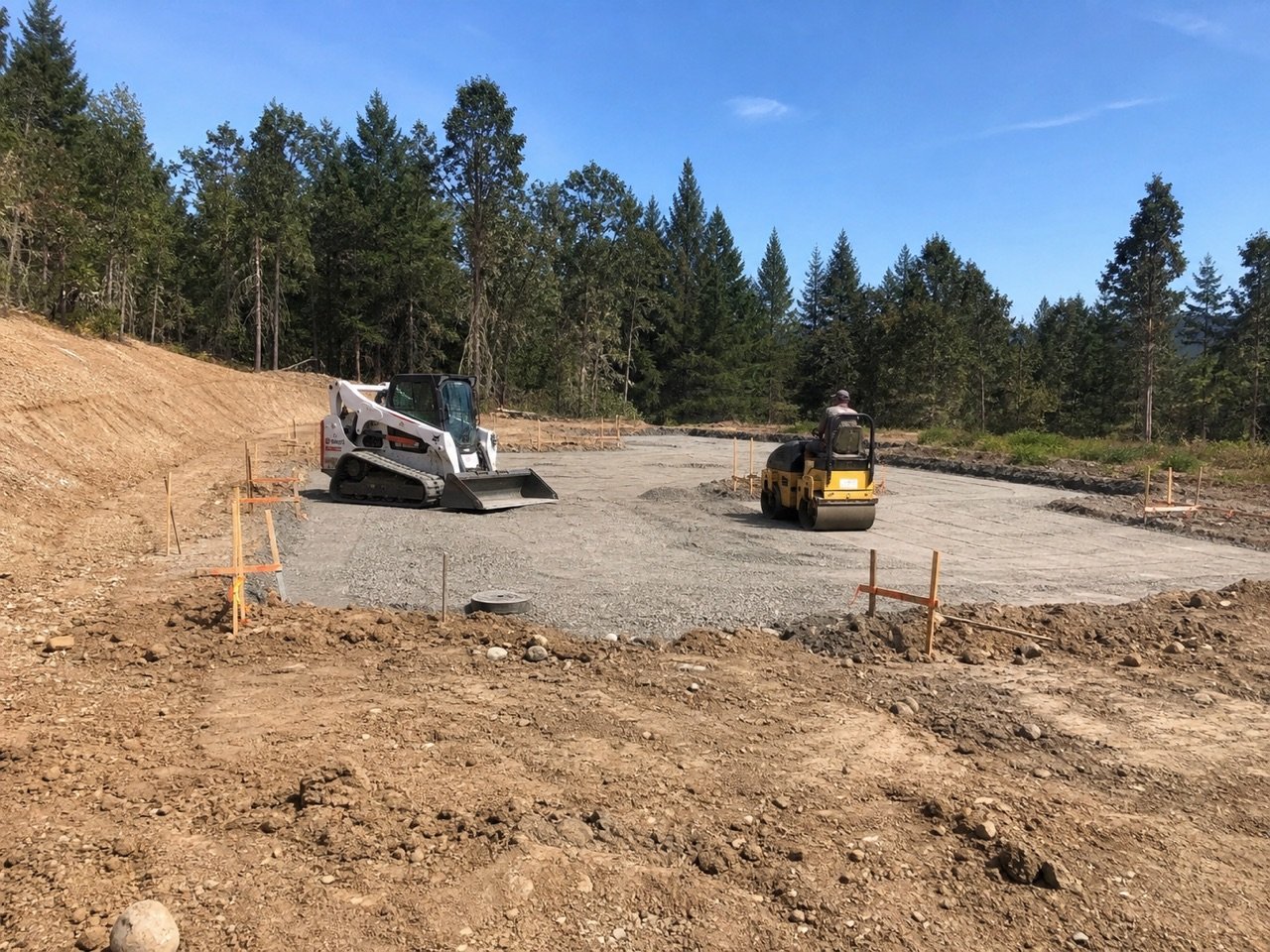 Track loader and compactor preparing a foundation pad